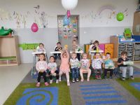 Dwanaścioro dzieci pozujących do zdjęcia na tle ściany w sali klubu dziecięcego