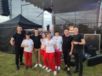Trzy członkinie KGW Dzedziczki z zespołem Playboys przy scenie na Święcie Truskawki